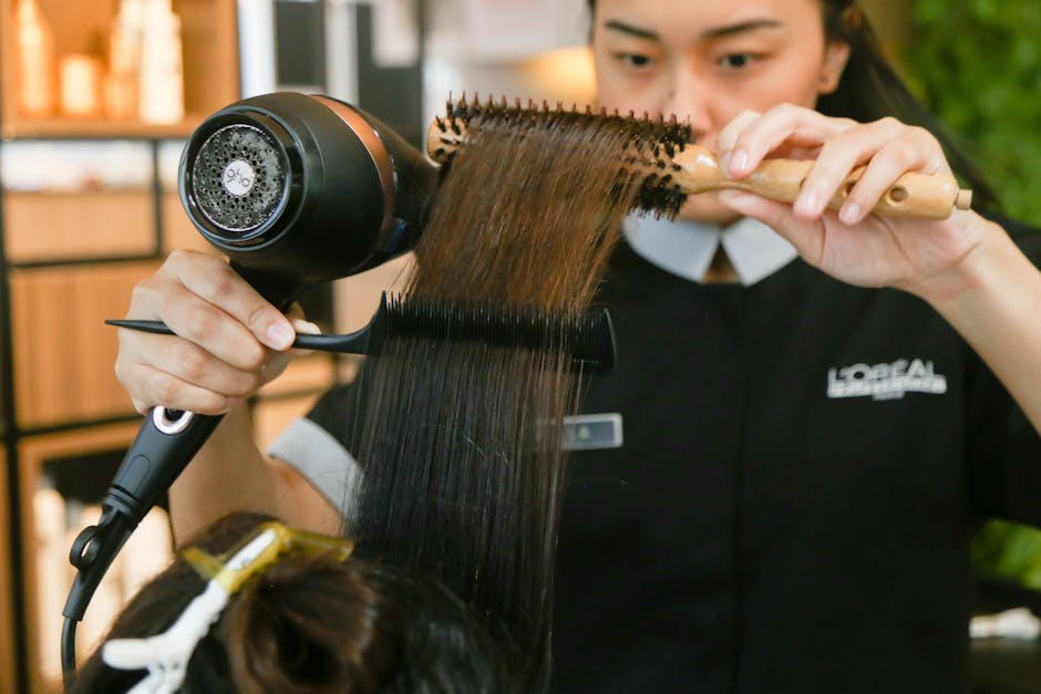 Hairdresser expertly styles hair using a brush and dryer in a salon setting